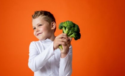 Boy holding head of broccoli                               
